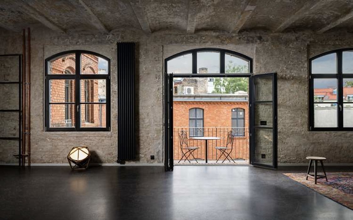 Loft with exposed concrete ceiling and arched windows